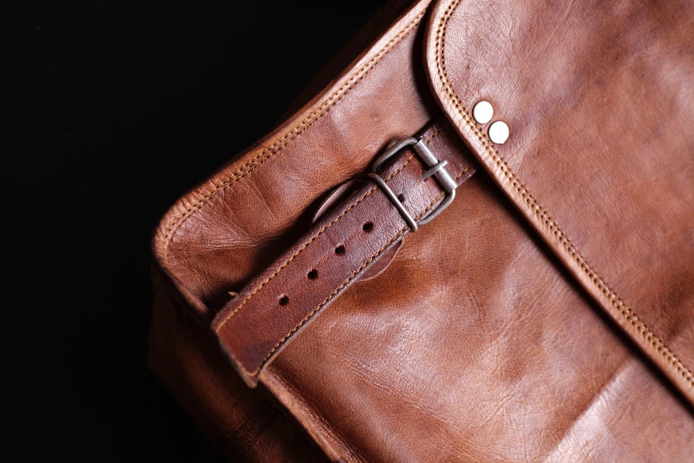 Close-up of a brown leather bag with a strap and buckle from Ridge N Threads