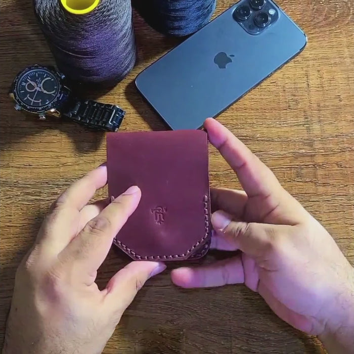 Hand holding the Article No 805 Slim flip Wallet near accessories like phone and watch, showcasing its compact, durable leather design.