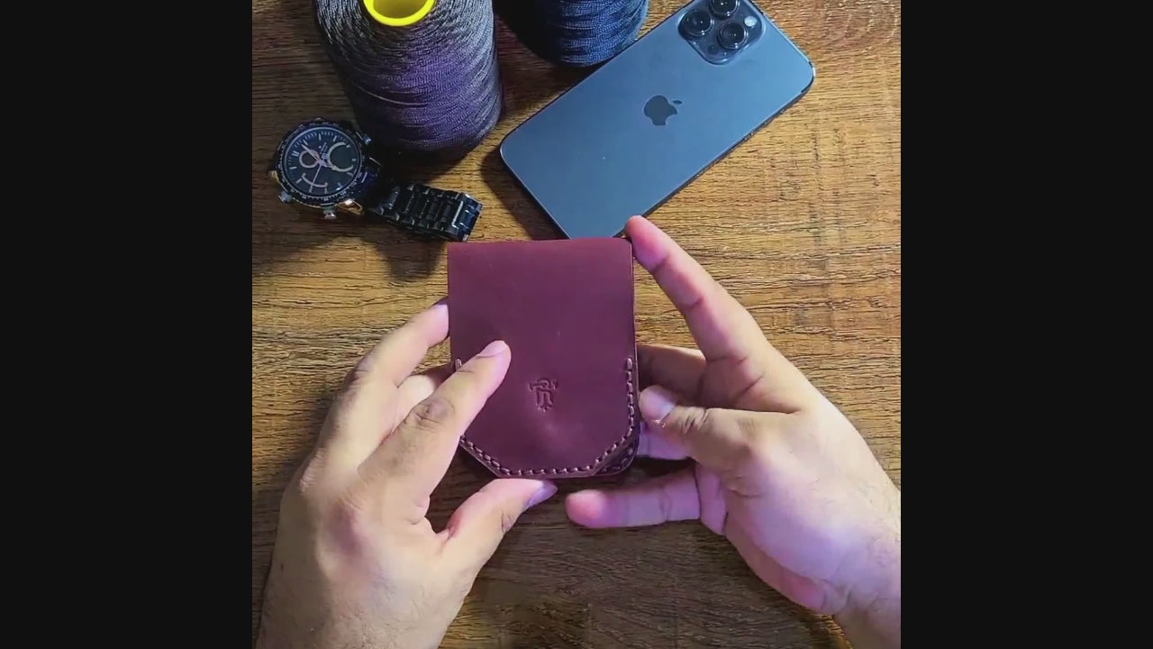Hand holding the Article No 805 Slim flip Wallet near accessories like phone and watch, showcasing its compact, durable leather design.