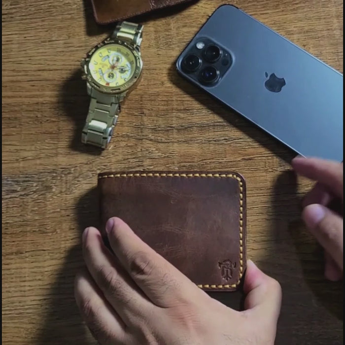 Lifestyle shot of Article No 101 Bifold Leather Wallet on wooden surface beside watch and smartphone, emphasizing its stylish appeal.