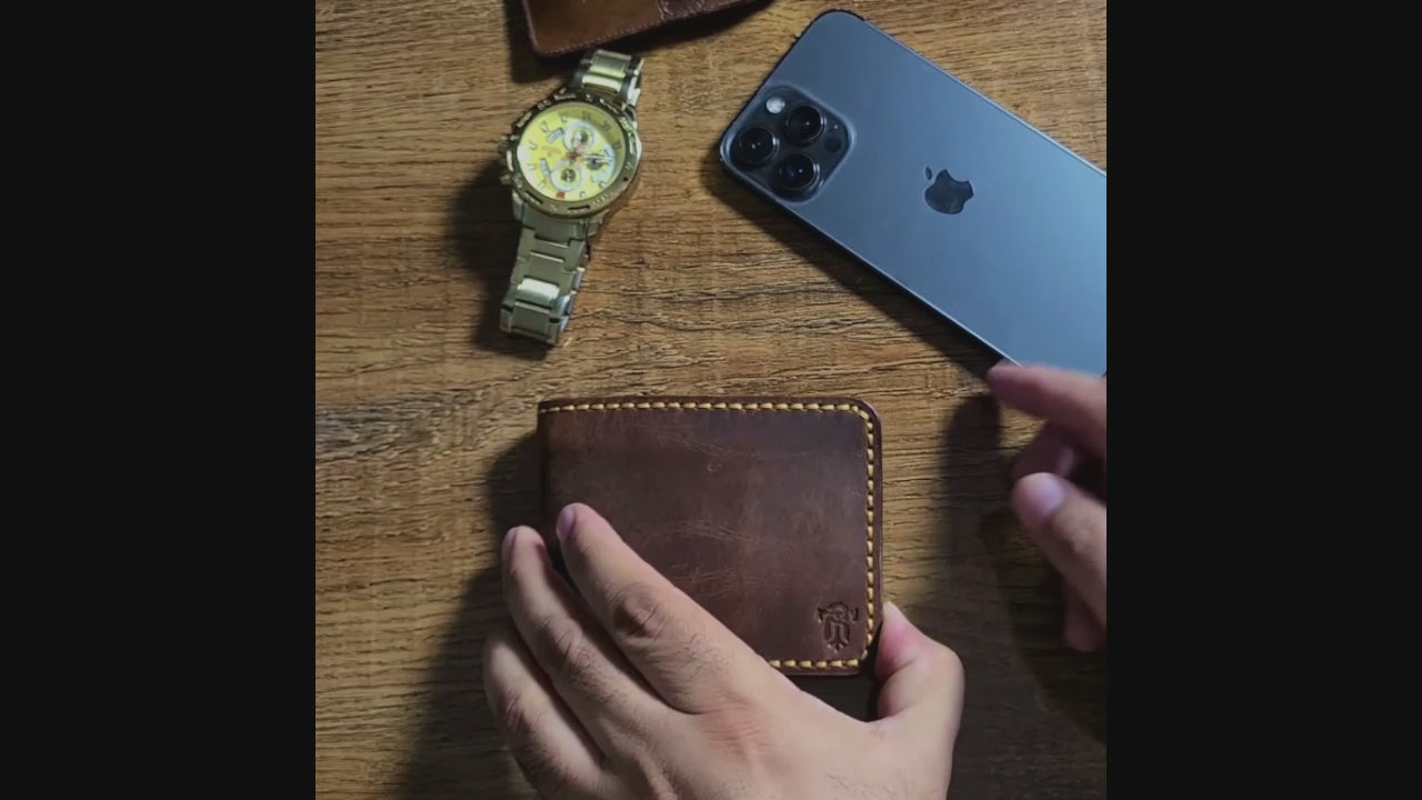 Lifestyle shot of Article No 101 Bifold Leather Wallet on wooden surface beside watch and smartphone, emphasizing its stylish appeal.